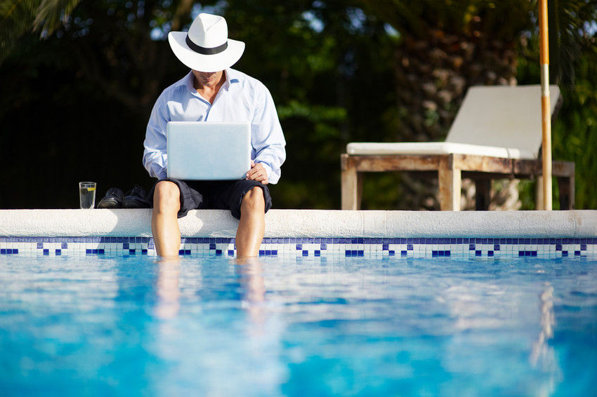 Man using his computer by a pool